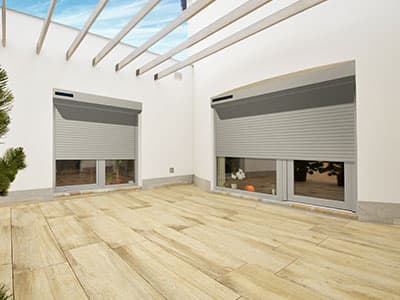 Deux volets roulants solaires gris sur une terrasse moderne avec un sol en bois.