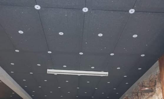 Panneaux d'isolation gris foncé fixés au plafond par des attaches blanches circulaires avec un luminaire.